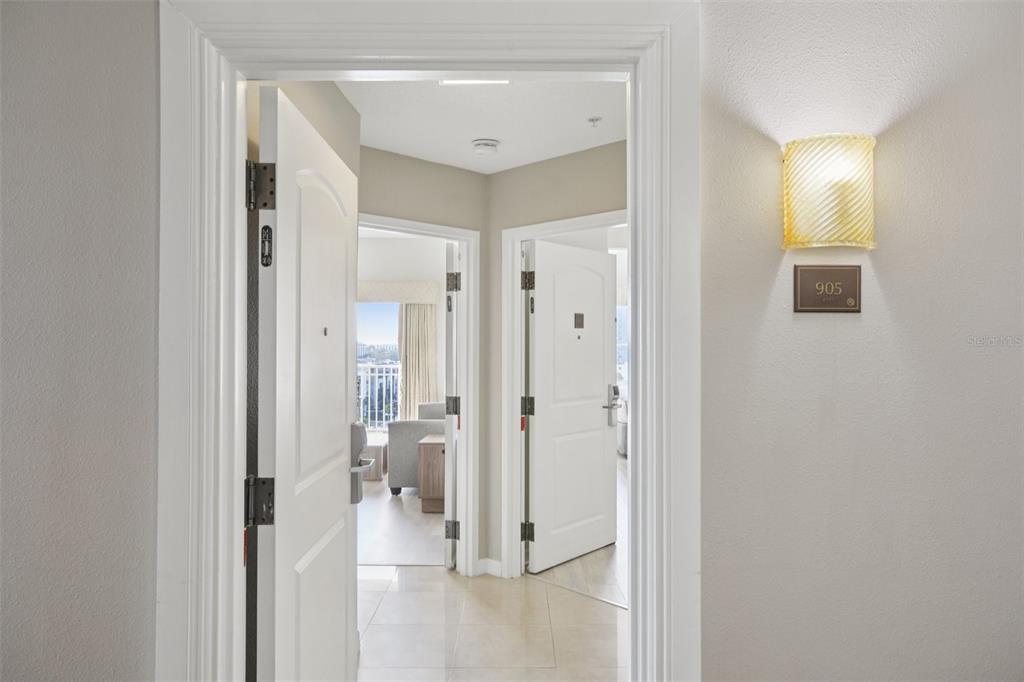 A view through an open doorway into a hallway with two white interior doors — 7395 UNIVERSAL BOULEVARD UNIT 905, ORLANDO, FL