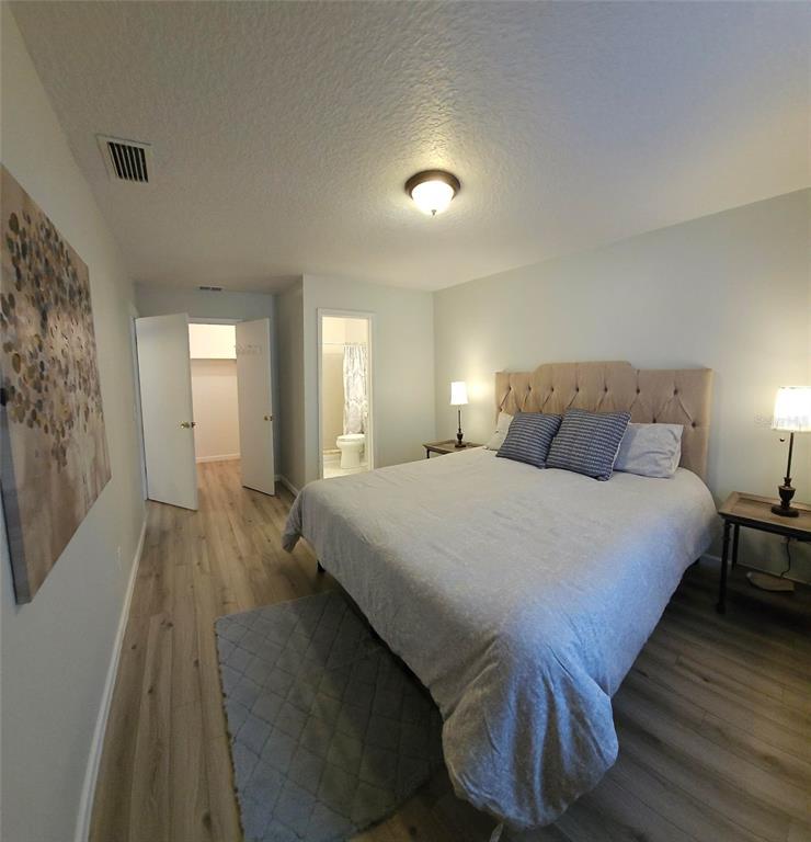 A bedroom features a tufted headboard, wood-look flooring, a walk-in closet, and an attached bathroom — 819 WALNUT PLACE, ALTAMONTE SPRINGS, FL