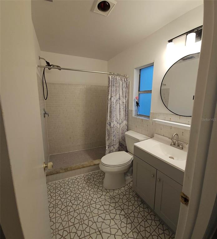 A bathroom features a walk-in tiled shower, a white toilet, and a gray vanity cabinet — 819 WALNUT PLACE, ALTAMONTE SPRINGS, FL