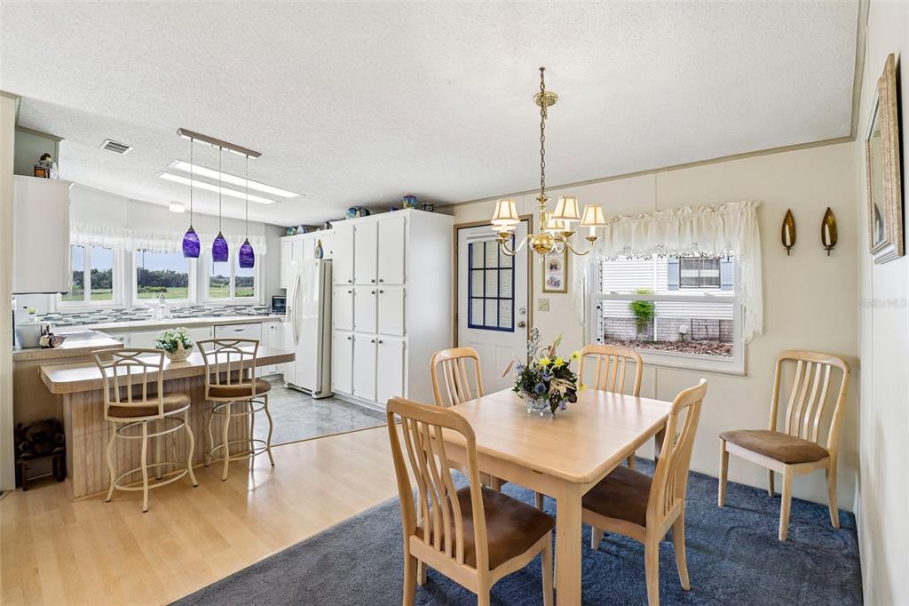 A dining area with a wooden table and chairs sits adjacent to a kitchen with bar seating — 25120 CLIFFORD HILL, LEESBURG, FL