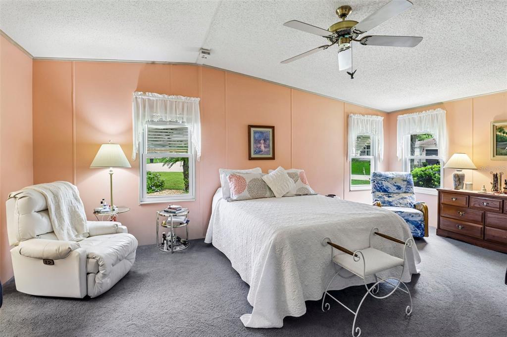 A bedroom with peach walls, a white bed, a white recliner, and a ceiling fan — 25120 CLIFFORD HILL, LEESBURG, FL