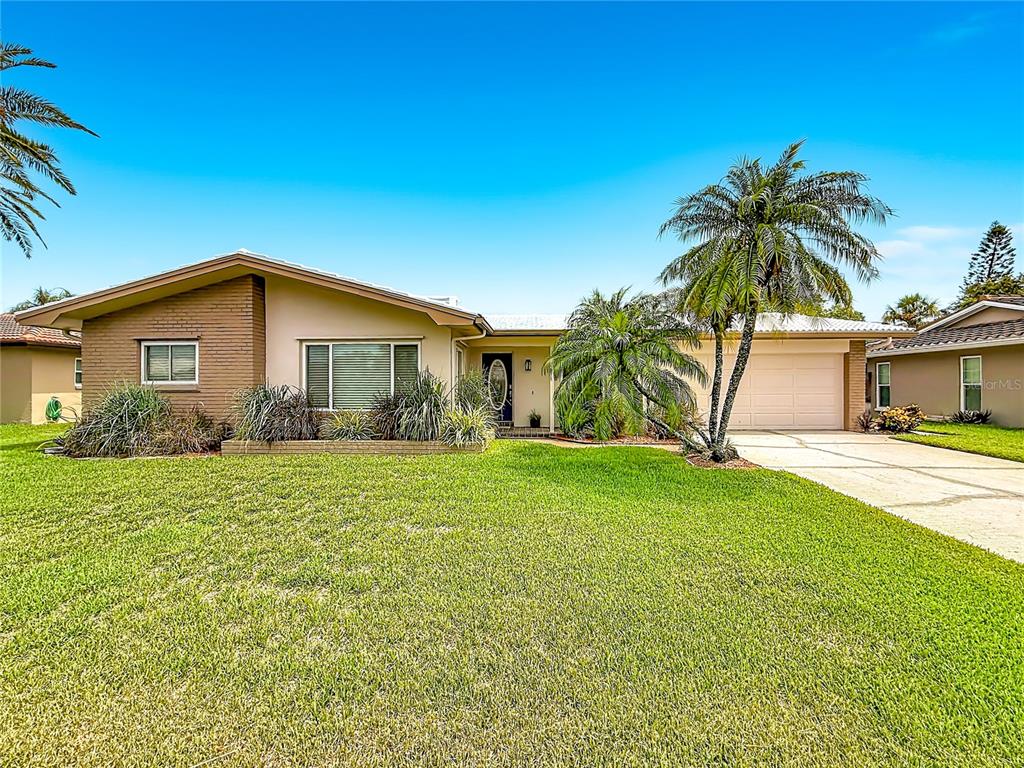 A single-story house with a brick facade, a large lawn, and a palm tree — 2178 WATERSIDE DRIVE, CLEARWATER, FL