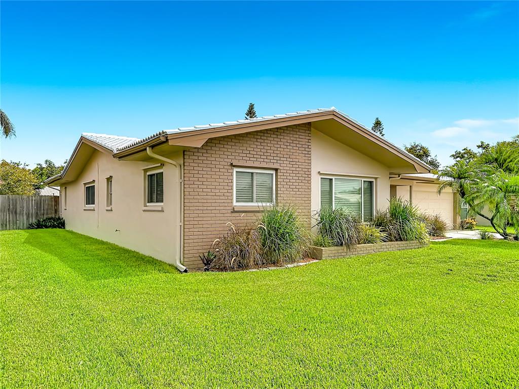 A single-story house with a brick facade, beige siding, and a green lawn — 2178 WATERSIDE DRIVE, CLEARWATER, FL