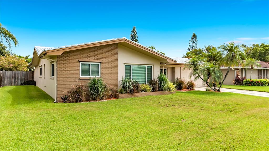 A single-story house with a brick facade, a large front lawn, and palm trees — 2178 WATERSIDE DRIVE, CLEARWATER, FL