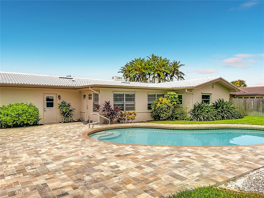 A backyard features a swimming pool, a paved patio, and a single-story house exterior — 2178 WATERSIDE DRIVE, CLEARWATER, FL