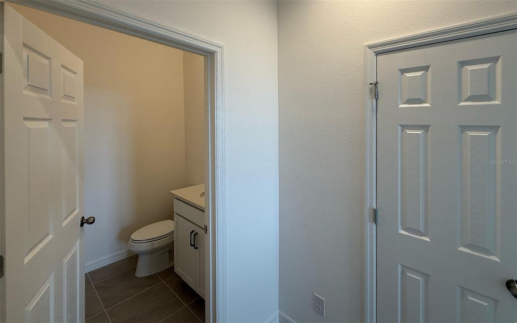 A hallway features a doorway leading to a small bathroom with a toilet and vanity — 6708 SPOTTED EAGLE LOOP, HOWEY IN THE HILLS, FL