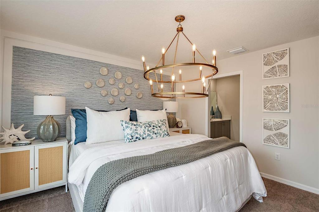 A bedroom features a textured blue accent wall, a large chandelier, and a white bed — 4251 HILLOCK BOULEVARD, HAINES CITY, FL