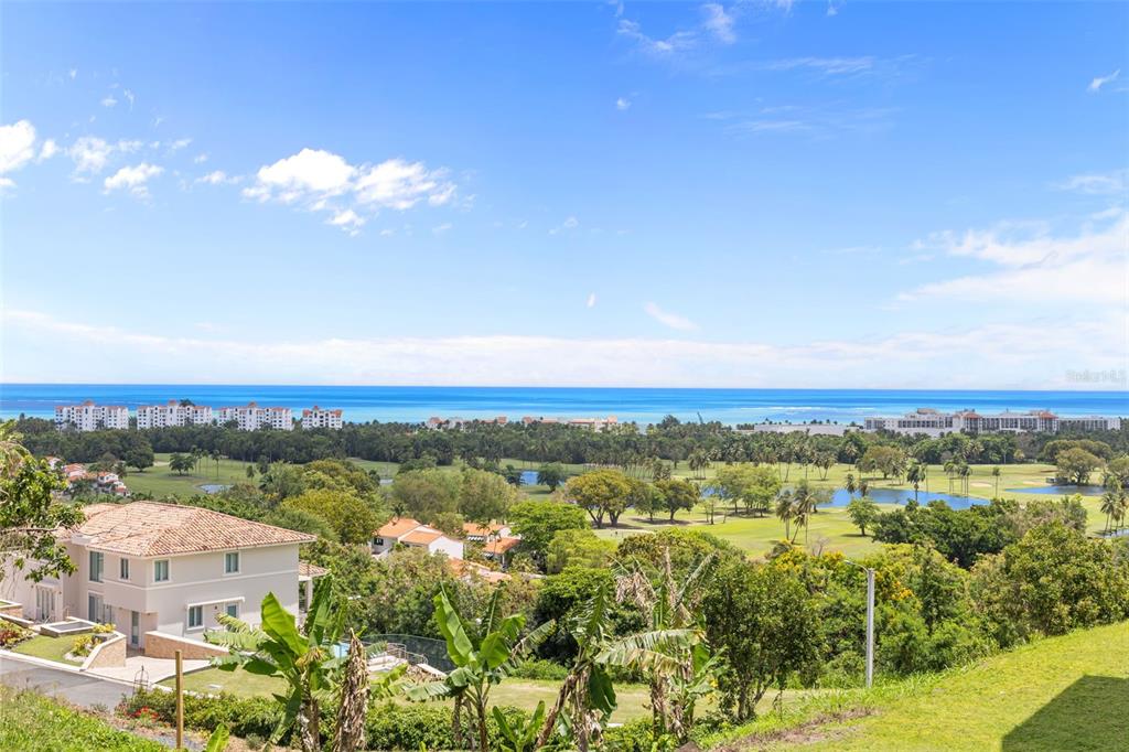 An elevated view shows a residential house, a golf course, and the ocean beyond — Las Vistas 36,  Rio Mar MIRADOR, 36, RIO MAR, RIO GRANDE, PR