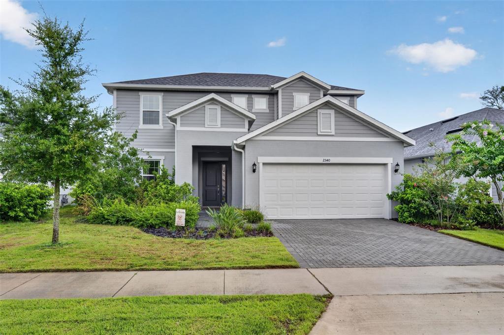 A two-story gray house features a two-car garage, a covered entryway, and a paved driveway — 2340 SIRENA LANE, MOUNT DORA, FL
