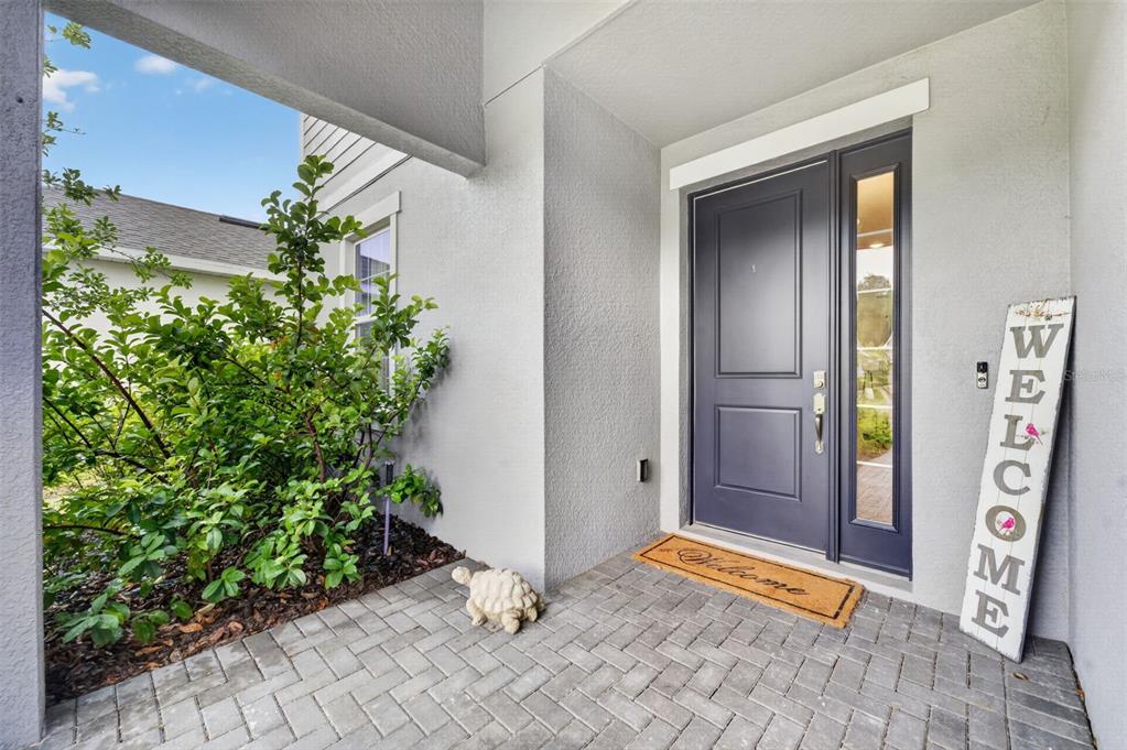 A covered entryway features a dark blue front door, a welcome sign, and a turtle statue — 2340 SIRENA LANE, MOUNT DORA, FL