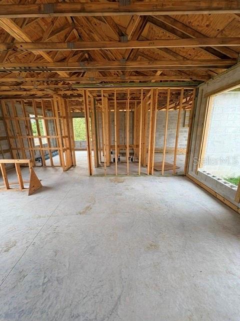 An unfinished room with exposed wooden framing, a concrete floor, and a large window opening — 3505 39TH STREET SW, LEHIGH ACRES, FL