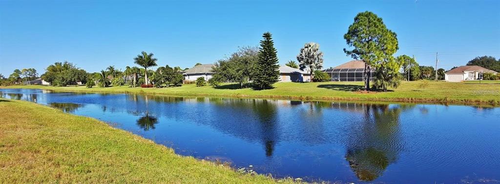 A wide view of a calm pond with houses and trees in the background — 847 ROTONDA CIRCLE, ROTONDA WEST, FL