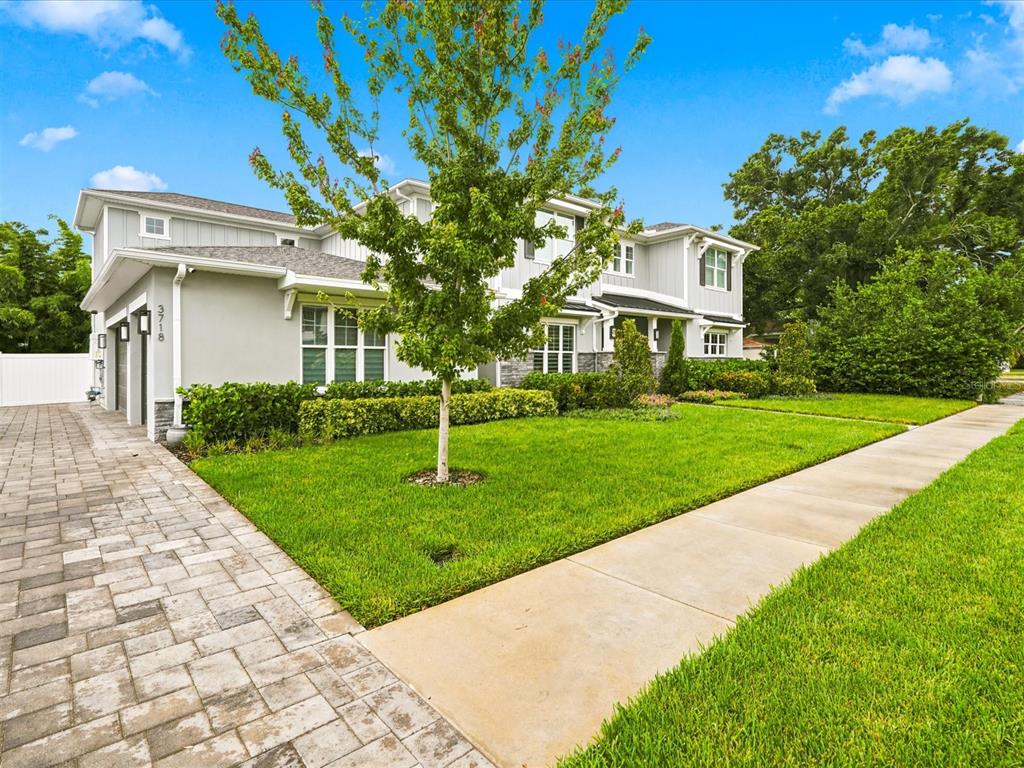 A two-story house with light gray siding, a paved driveway, and a manicured front lawn — 3718 W PALMIRA AVENUE, TAMPA, FL