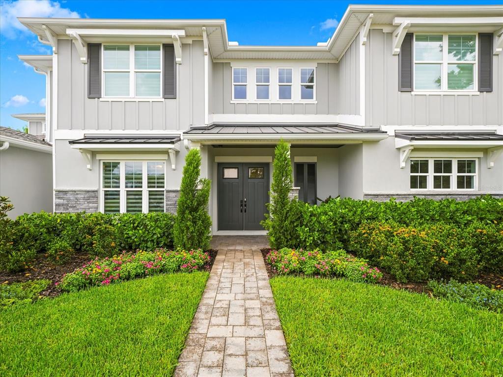 A two-story house exterior with gray siding, a stone base, and a paved walkway entrance — 3718 W PALMIRA AVENUE, TAMPA, FL