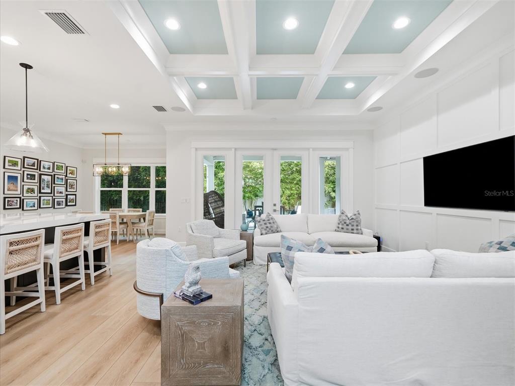 A bright living room features a coffered ceiling, white board-and-batten walls, and light wood flooring — 3718 W PALMIRA AVENUE, TAMPA, FL
