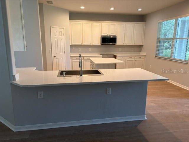 A kitchen with white cabinets, a central island, and a peninsula with a sink — 1885 SCRUB JAY RD., APOPKA, FL
