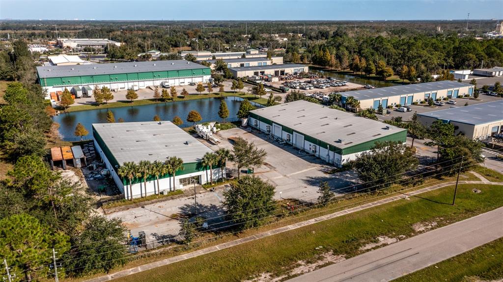 An aerial view shows several industrial warehouse buildings situated near a retention pond — 1780 BUSINESS CENTER LANE, KISSIMMEE, FL