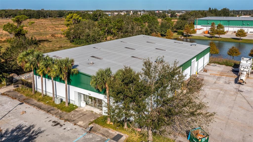 An aerial view shows a large industrial warehouse building with a metal roof and parking lot — 1780 BUSINESS CENTER LANE, KISSIMMEE, FL