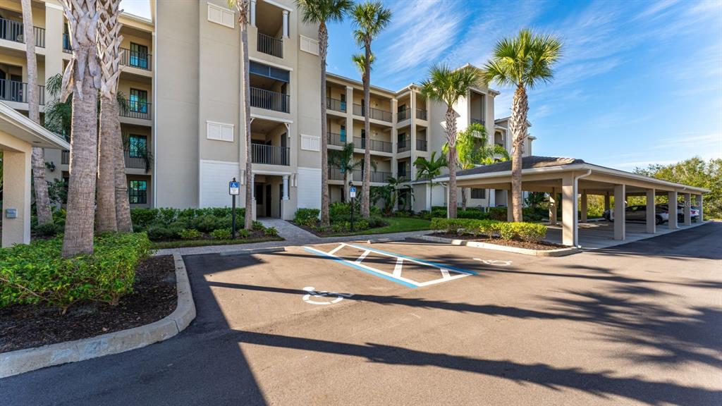 A multi-story apartment building features a covered parking area and a handicap-accessible parking space — 17510 GAWTHROP DRIVE UNIT 105, BRADENTON, FL