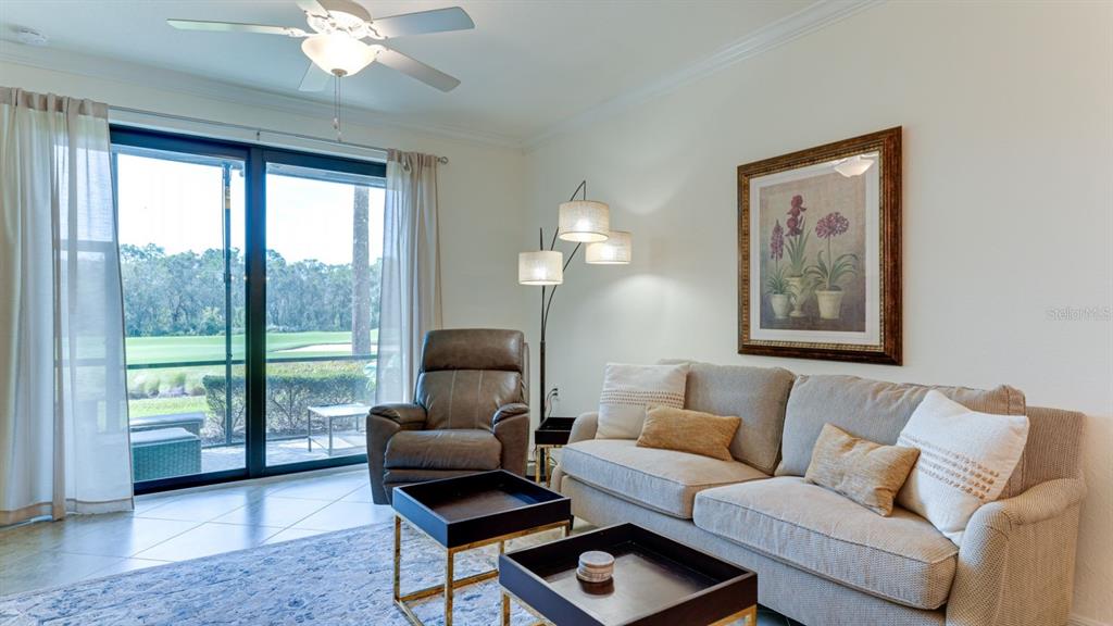 A living room features a beige sofa, leather recliner, two coffee tables, and sliding glass doors — 17510 GAWTHROP DRIVE UNIT 105, BRADENTON, FL
