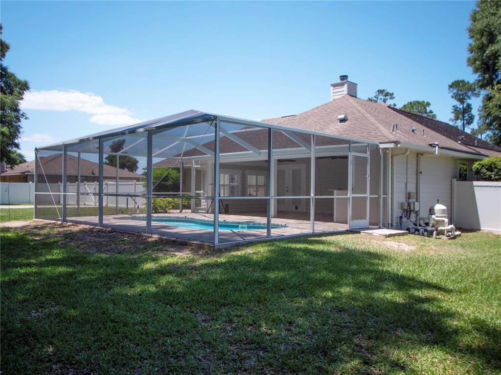A backyard view of a house with a screened-in pool enclosure and pool equipment — 1258 NE 51ST LOOP, OCALA, FL
