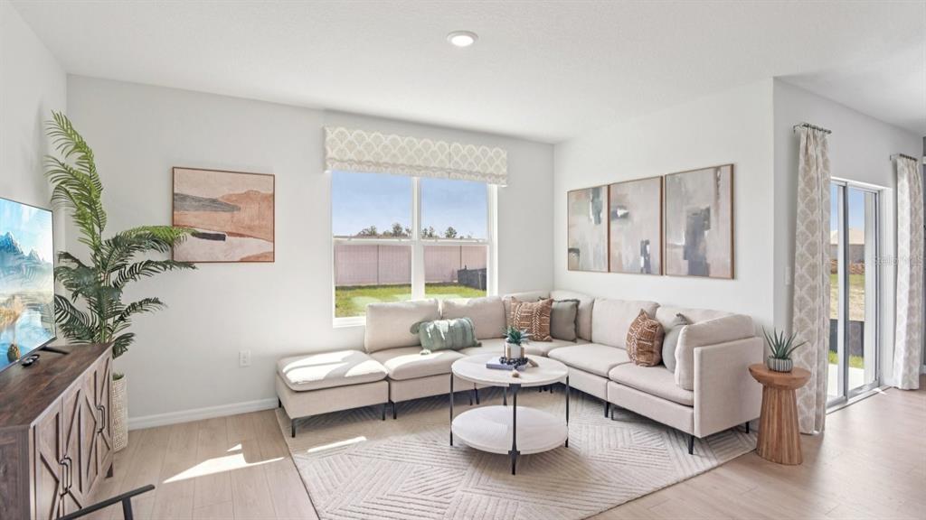 A living room features a beige sectional sofa, a round coffee table, and a large window — 1216 ALPINE ASH PLACE SE, RUSKIN, FL