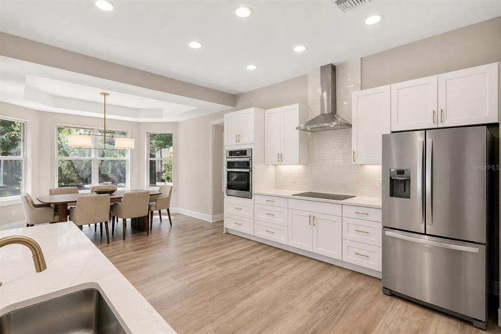 A modern open-concept living area features a kitchen island, curved sofa, and a staircase — 10370 TROUT ROAD, ORLANDO, FL