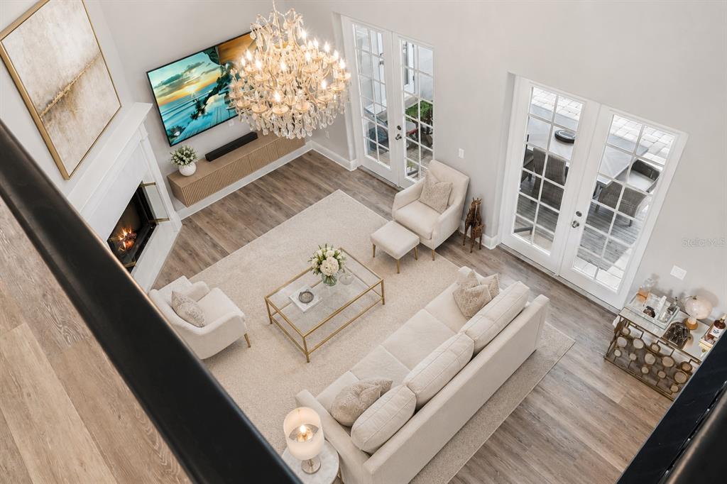 A high-angle view of a living room featuring a fireplace, chandelier, and neutral furniture — 10370 TROUT ROAD, ORLANDO, FL