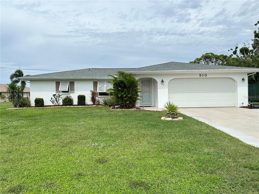 A single-story white house with a two-car garage and a green lawn — 910 CAPLES STREET, ENGLEWOOD, FL