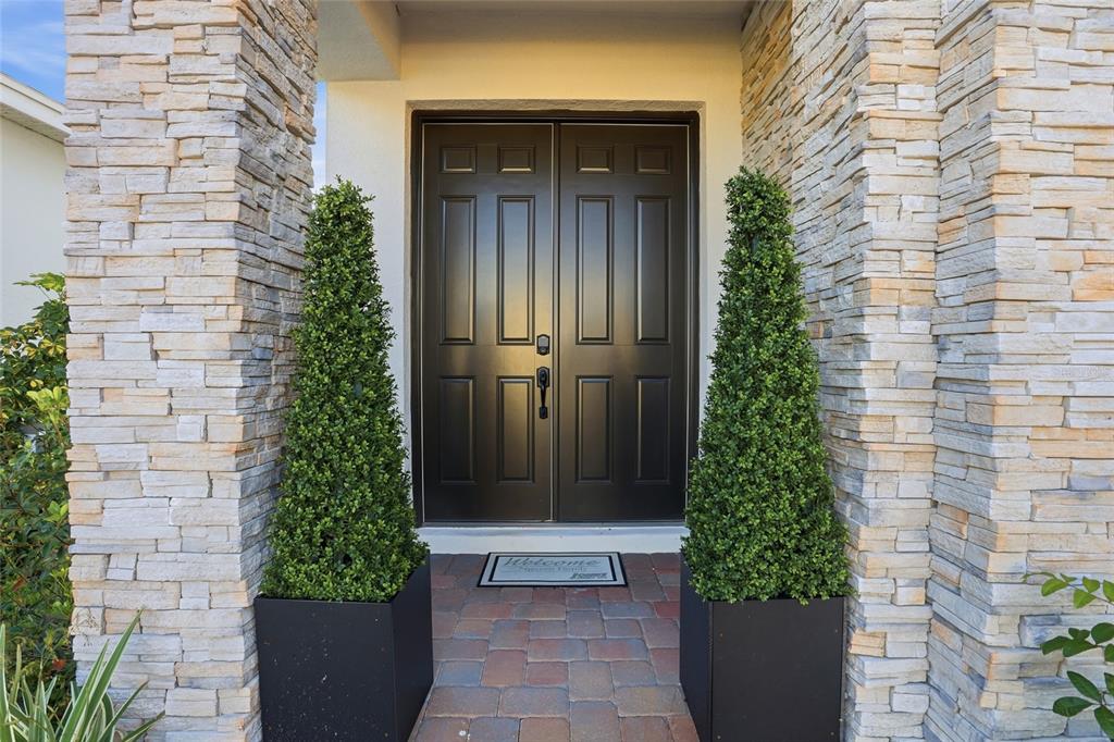 A front entrance features a double door flanked by two tall topiaries and stone pillars — 5170 BUTTONSAGE, ST CLOUD, FL