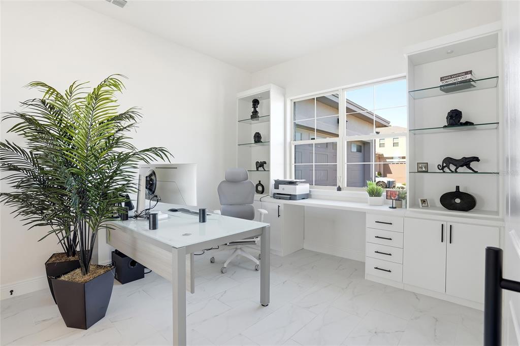 A home office features a white desk, built-in shelving, a gray chair, and a potted plant — 5170 BUTTONSAGE, ST CLOUD, FL