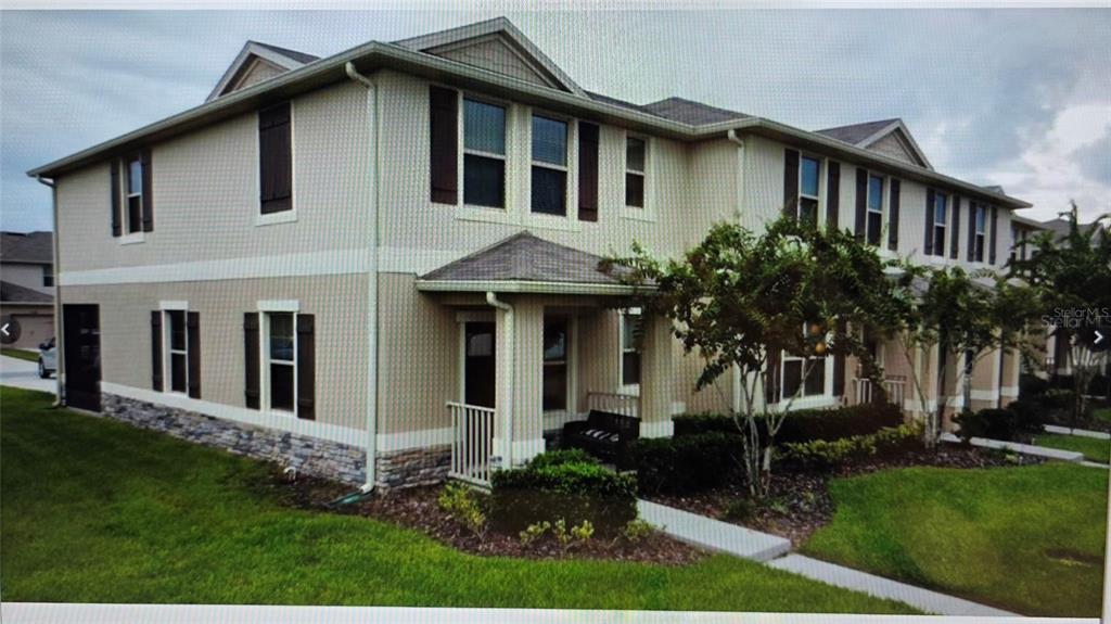 A two-story tan stucco townhouse with a garage, screened patio, and solar panels on roof — 1854 KATZ CROSSING DRIVE, KISSIMMEE, FL