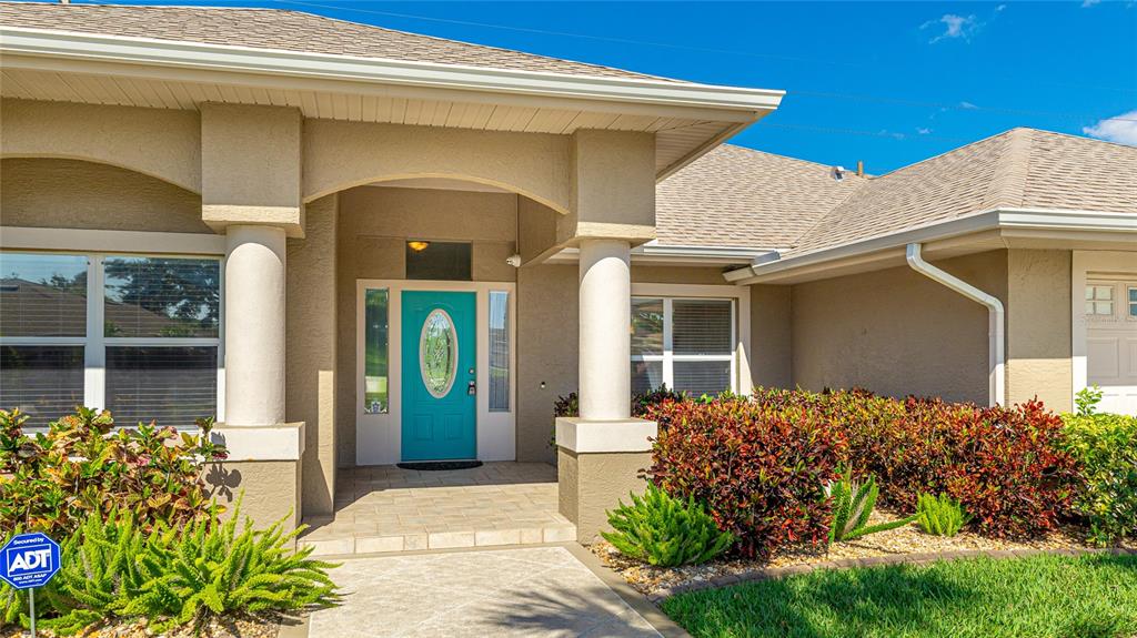 The exterior of a house features a teal front door, columns, and landscaped bushes — 534 OAK BAY DRIVE, OSPREY, FL