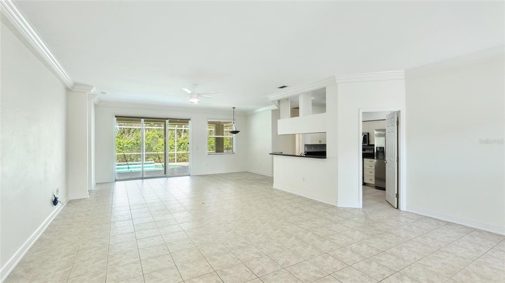 An open-concept living area features light tile flooring, a breakfast bar, and sliding glass doors — 534 OAK BAY DRIVE, OSPREY, FL