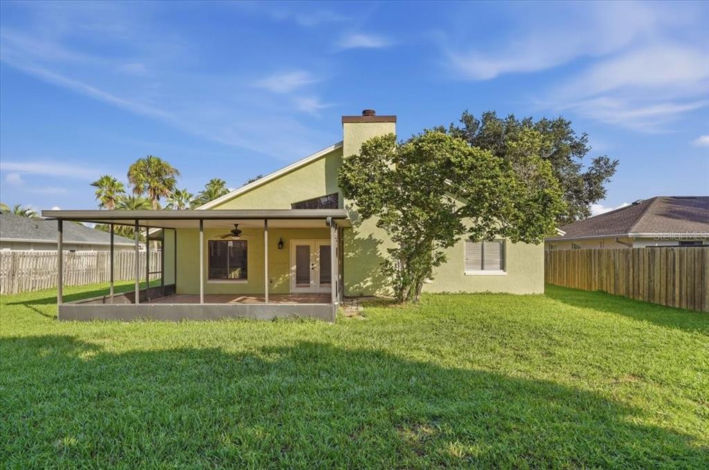 A single-story green house with a two-car garage, a screened entryway, and a large lawn — 20828 MAXIM PARKWAY, ORLANDO, FL