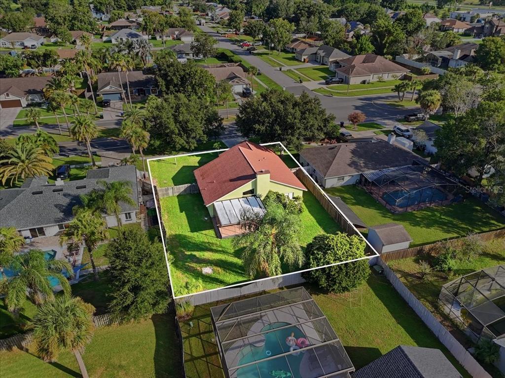 The exterior of a light green house features a screened-in patio and a large backyard — 20828 MAXIM PARKWAY, ORLANDO, FL
