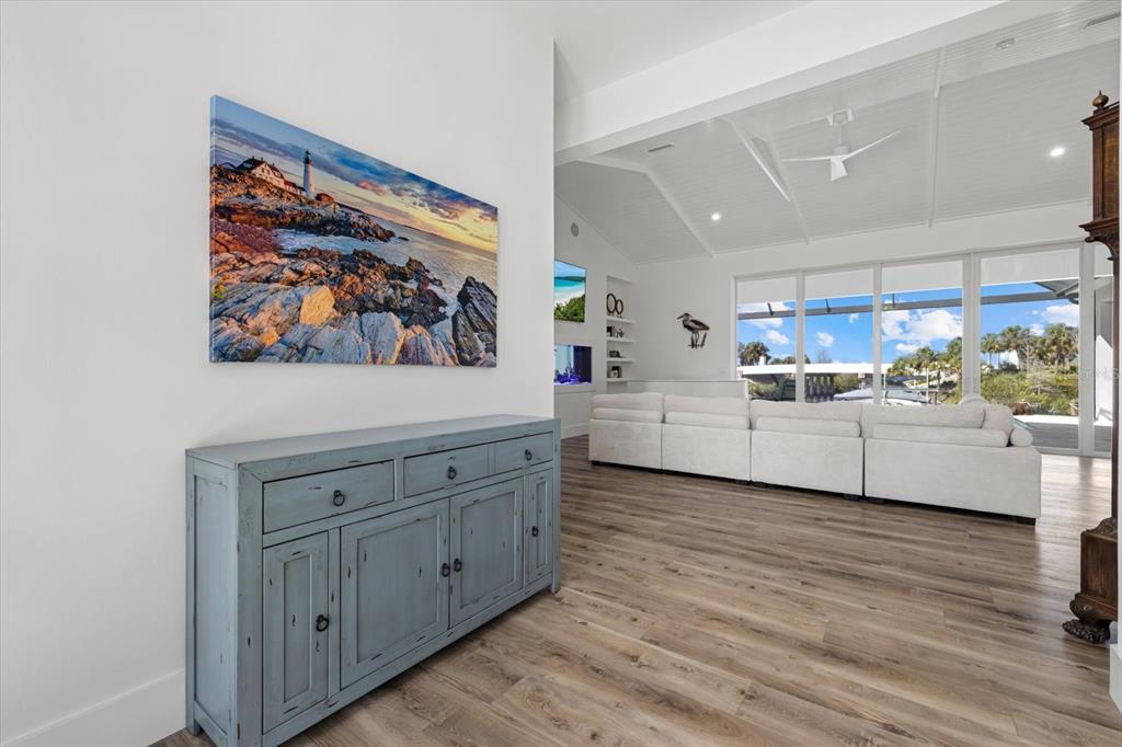 A blue wooden console table sits in a white room with wood-look flooring and furniture — 1831 RIO VISTA TERRACE, PARRISH, FL