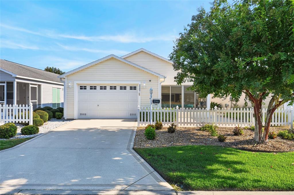 A single-story house with light siding, a white garage door, and a white picket fence — 2207 JETTA WAY, THE VILLAGES, FL