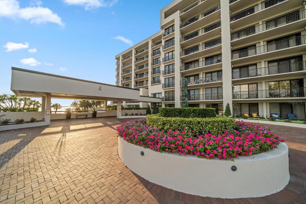 A multi-story apartment building features a paved circular driveway and a large flower bed — 4 BELLEVIEW BOULEVARD UNIT 106, BELLEAIR, FL