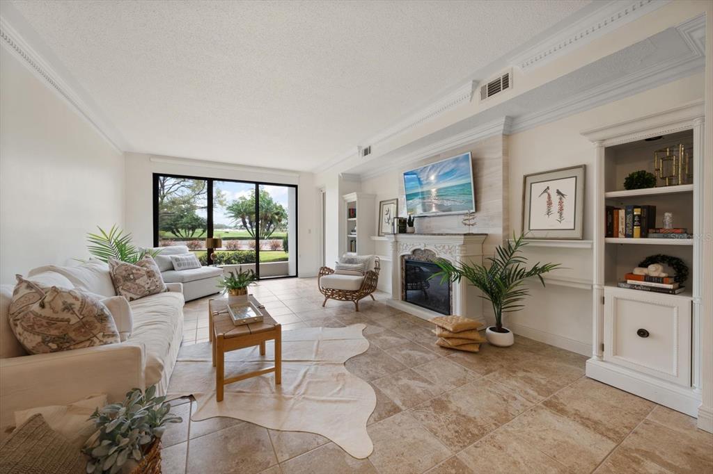 A living room features a fireplace, tile flooring, built-in shelving, and a glass sliding door — 4 BELLEVIEW BOULEVARD UNIT 106, BELLEAIR, FL