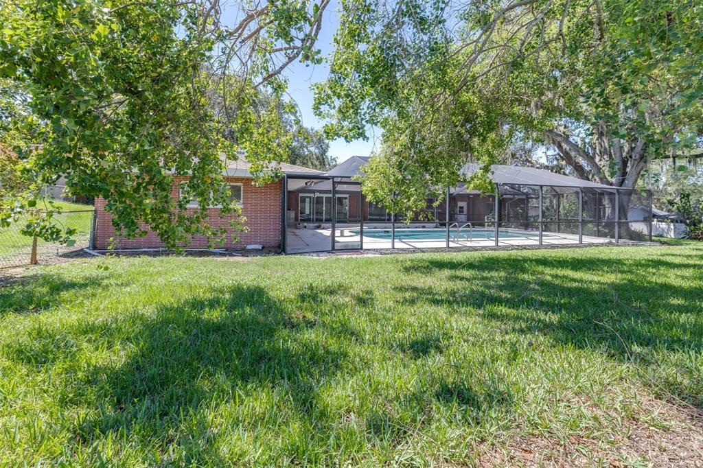 A brick house with a screened-in pool and large trees in the backyard — 300 CREST DRIVE, HAINES CITY, FL