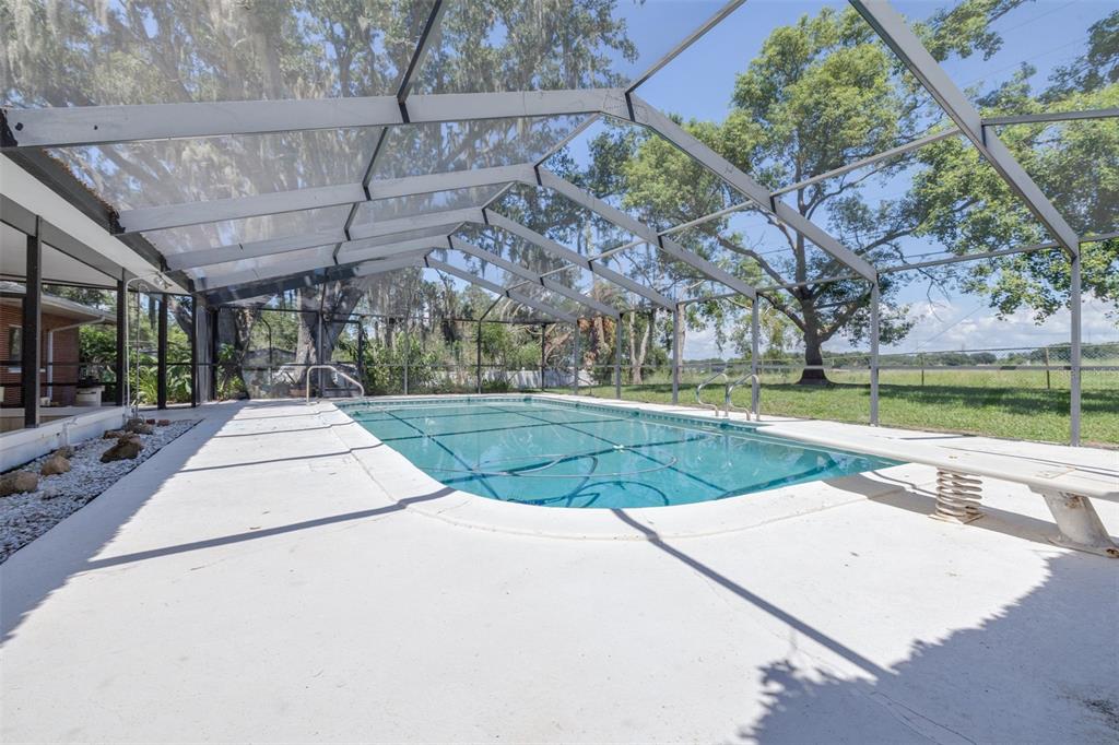 A rectangular swimming pool is enclosed by a screened lanai with a diving board — 300 CREST DRIVE, HAINES CITY, FL