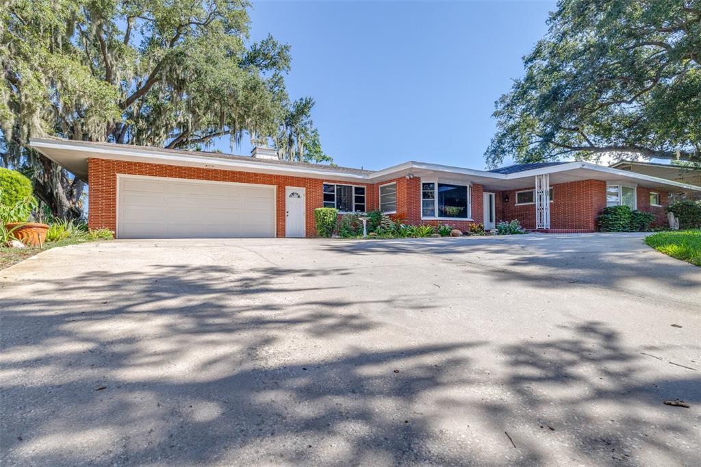 A single-story brick house with a large concrete driveway and a two-car garage — 300 CREST DRIVE, HAINES CITY, FL