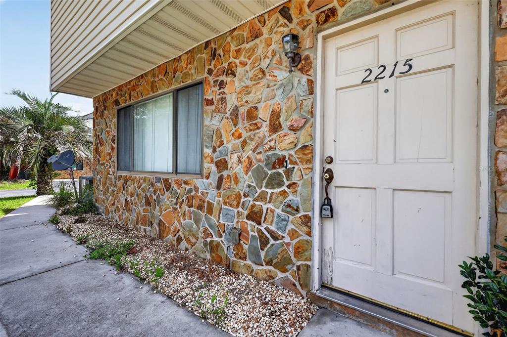 A stone-veneer exterior wall features a white door with the number 2215 and a window — 2215 NE 45TH AVENUE UNIT 3, OCALA, FL