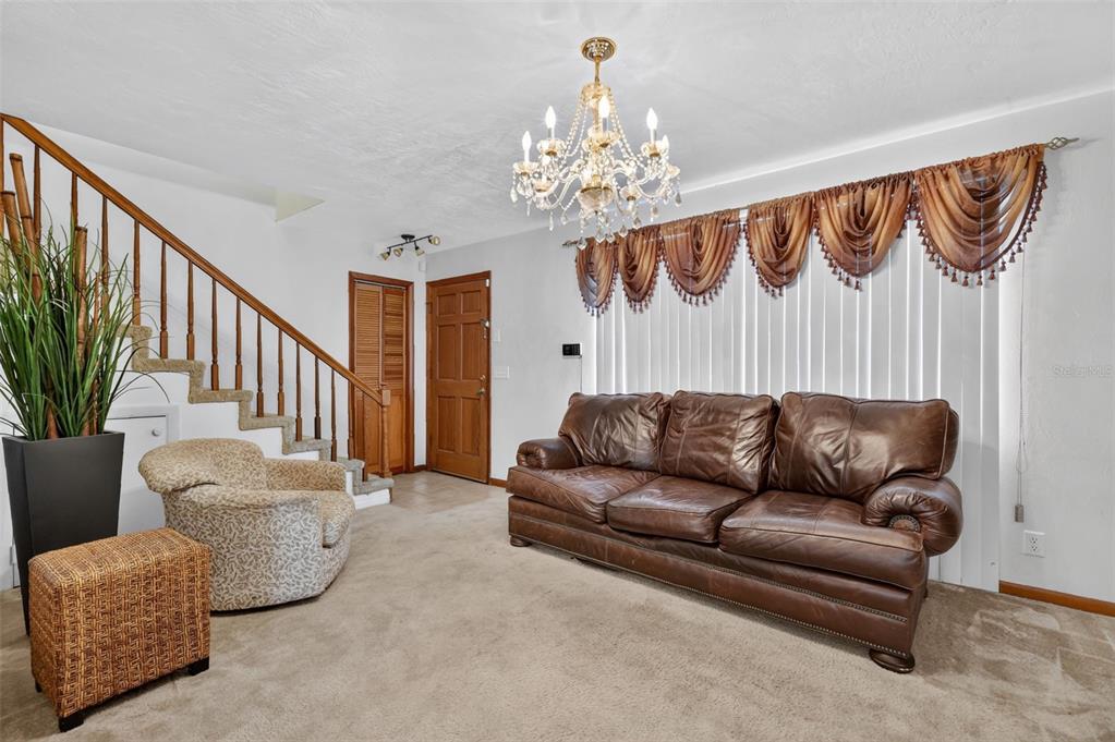 A living room features a brown leather sofa, a patterned armchair, and a crystal chandelier — 2215 NE 45TH AVENUE UNIT 3, OCALA, FL