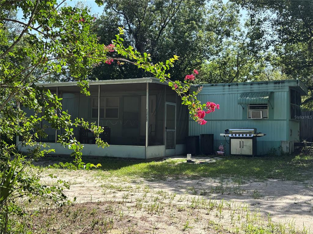A light-colored mobile home sits behind a tall black wooden privacy fence — 10416 HUDSON AVENUE, HUDSON, FL