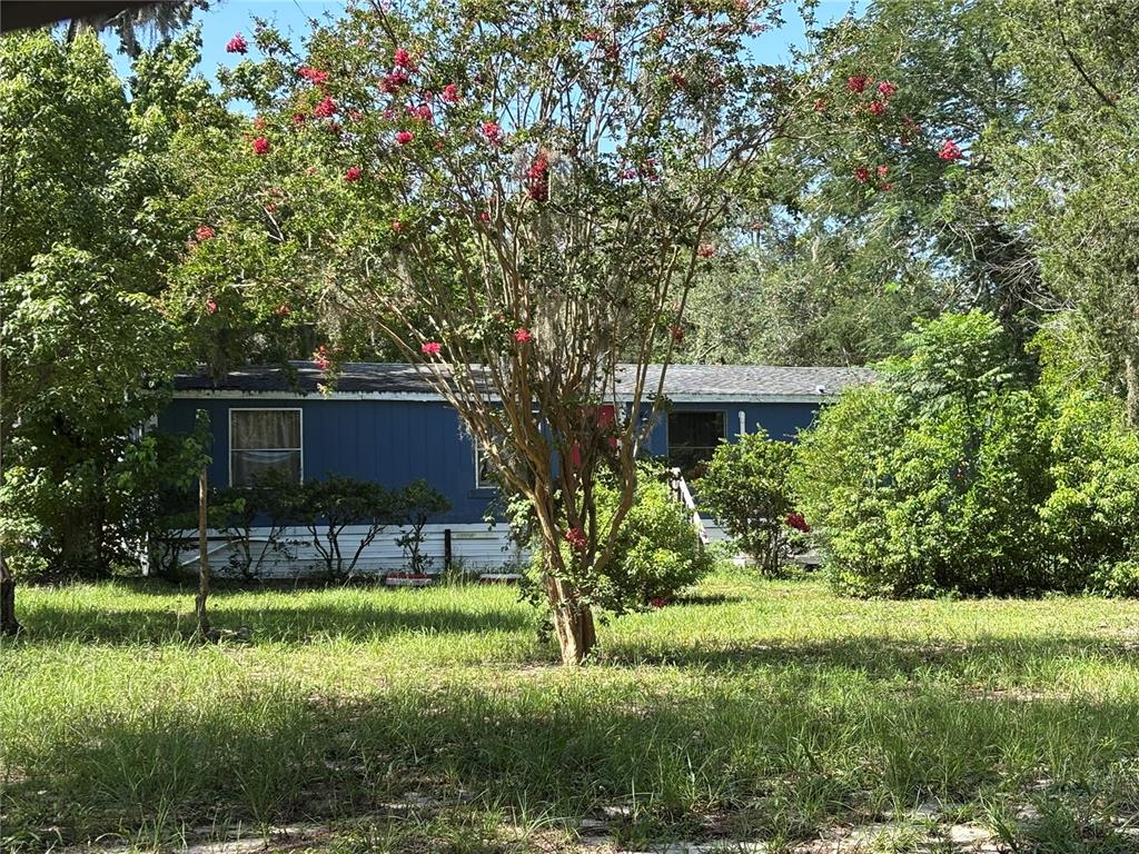 A mobile home with a screened-in porch and a grill sits on a sandy lot — 10416 HUDSON AVENUE, HUDSON, FL