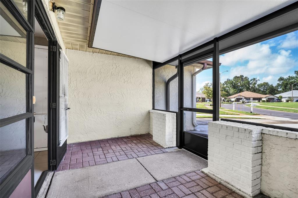 A screened-in porch with a brick paver floor, white brick walls, and a metal ceiling — 3472 MACLAREN DRIVE, PALM HARBOR, FL