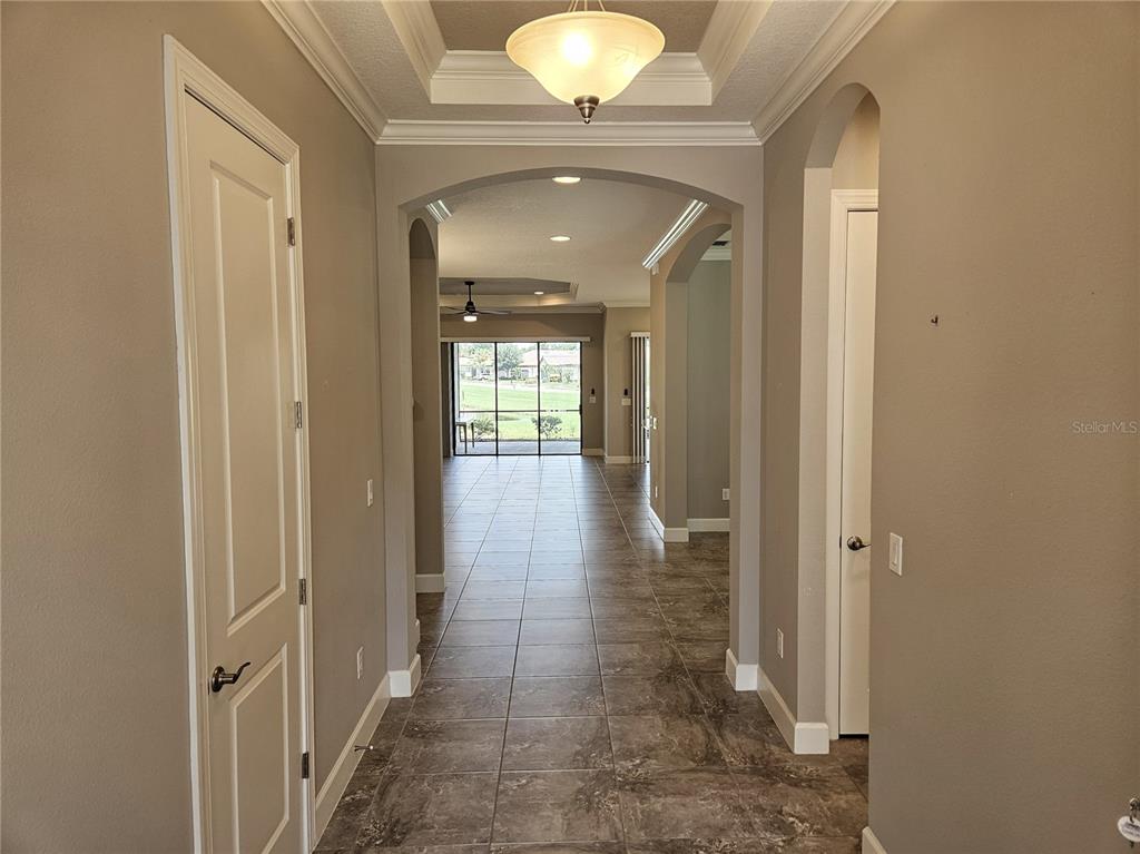 A tiled entryway leads through an arched hallway toward a living area with outdoor views — 5668 CANTUCCI STREET, NOKOMIS, FL