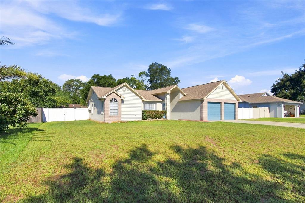 A single-story house with a two-car garage and a concrete driveway under a blue sky — 4745 CANTERBURY DRIVE, LAND O LAKES, FL